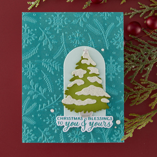 Christmas card with a snowy tree design and 'Christmas blessings to you & yours' text on a textured blue background.